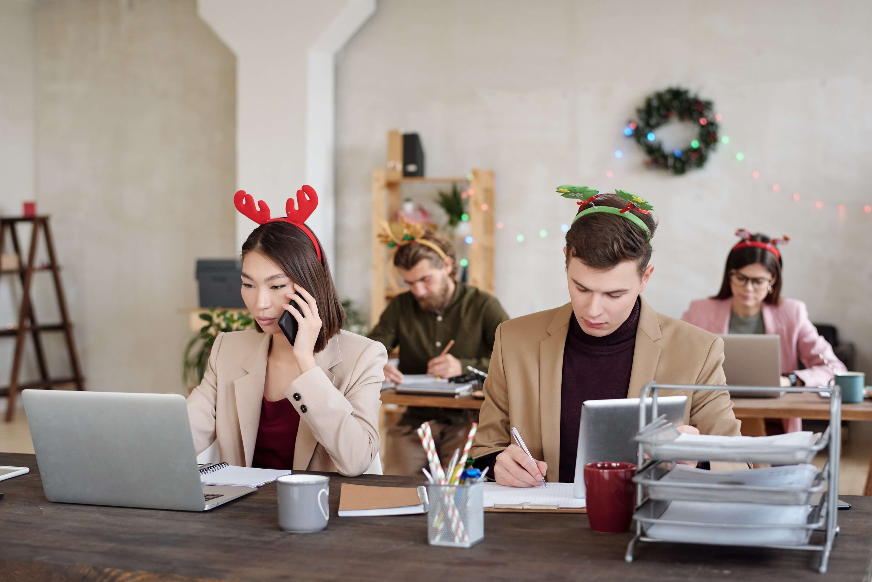 Young contemporary workers xmas headbands networking front laptops