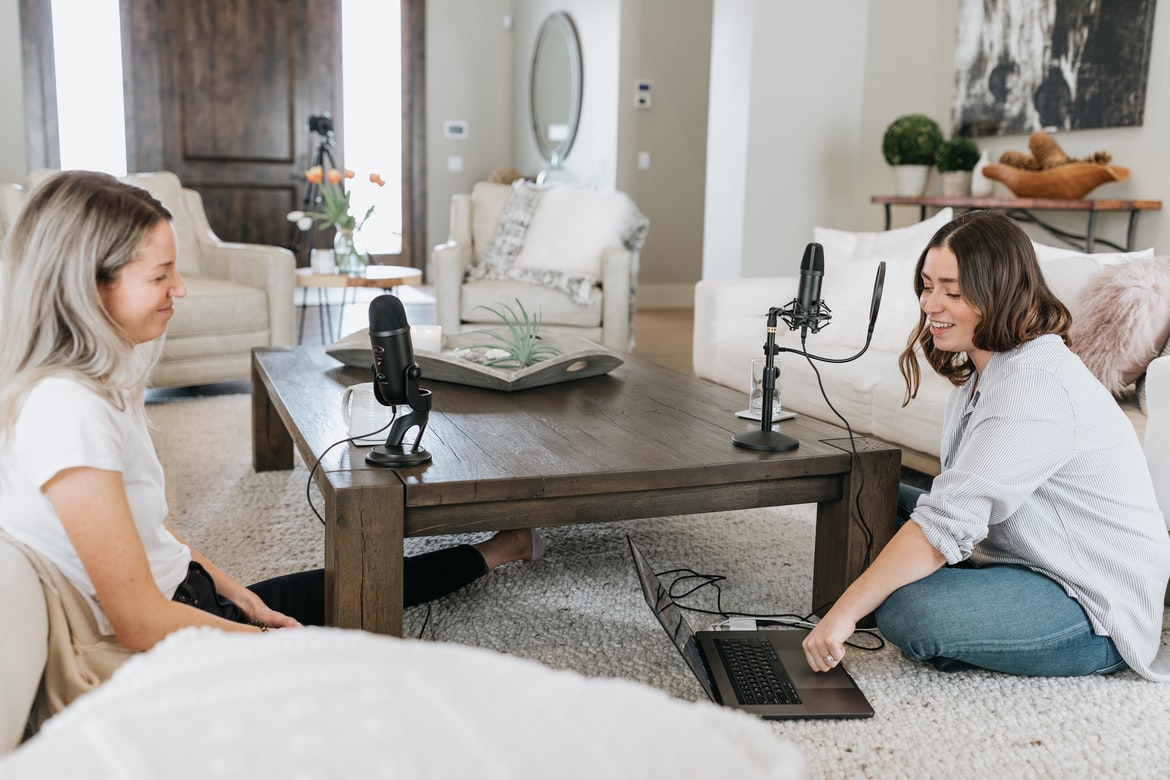 Two podcasters recording an episode in a living room