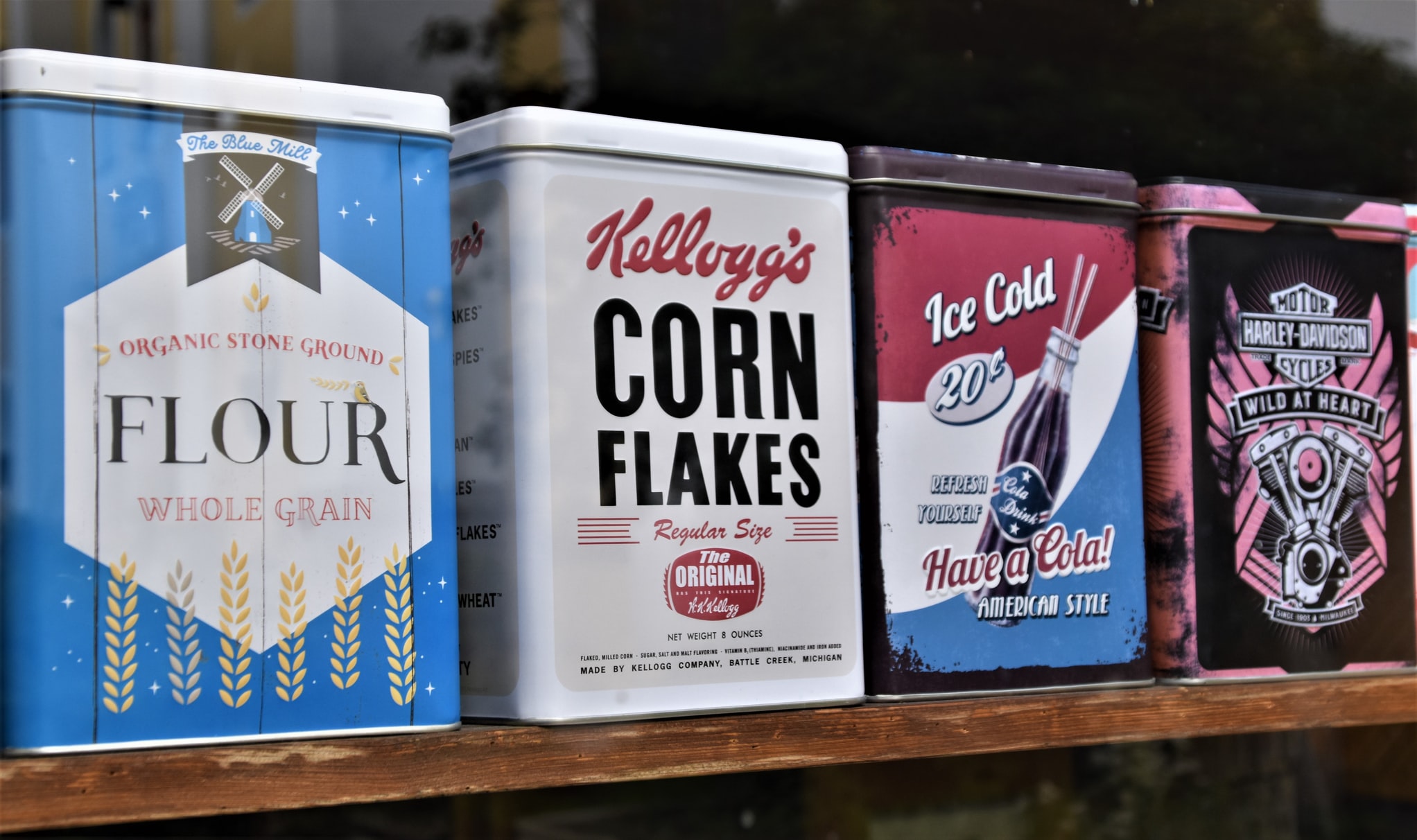 vintage tin can boxes of The Blue Mill, Kellogg's Corn Flakes, Lola Drink cola, and Harley Davidson Motorcycles
