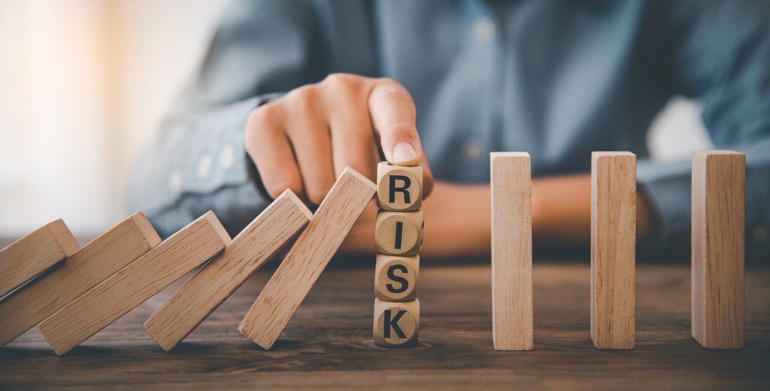 Businessman hand stopping domino effect with risk management blocks wooden table