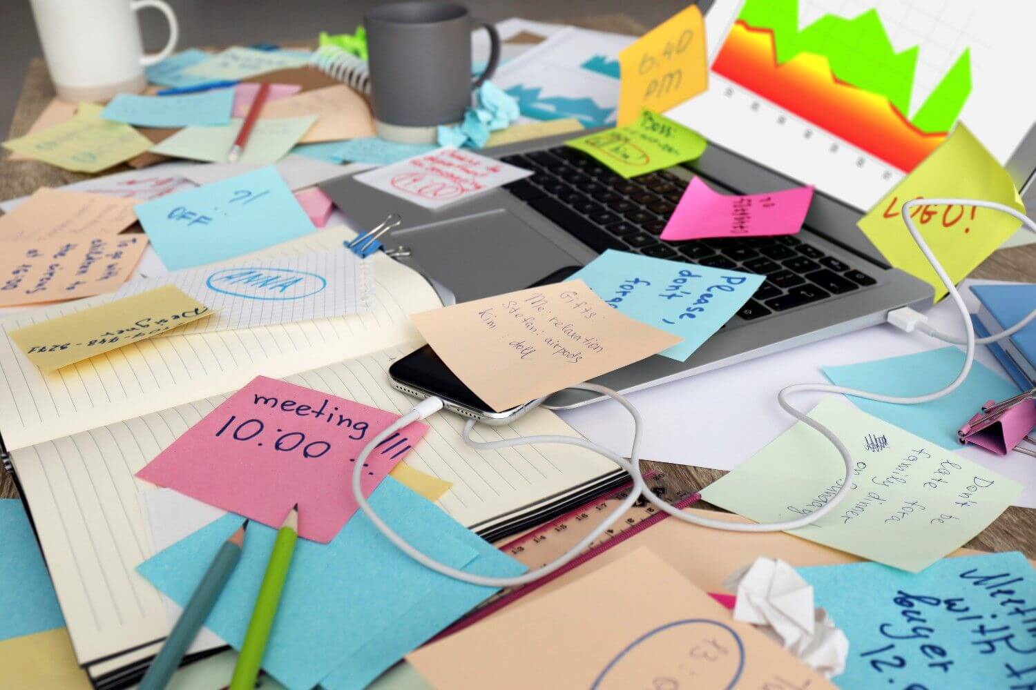 Laptop notes and office stationery mess desk overwhelmed with work