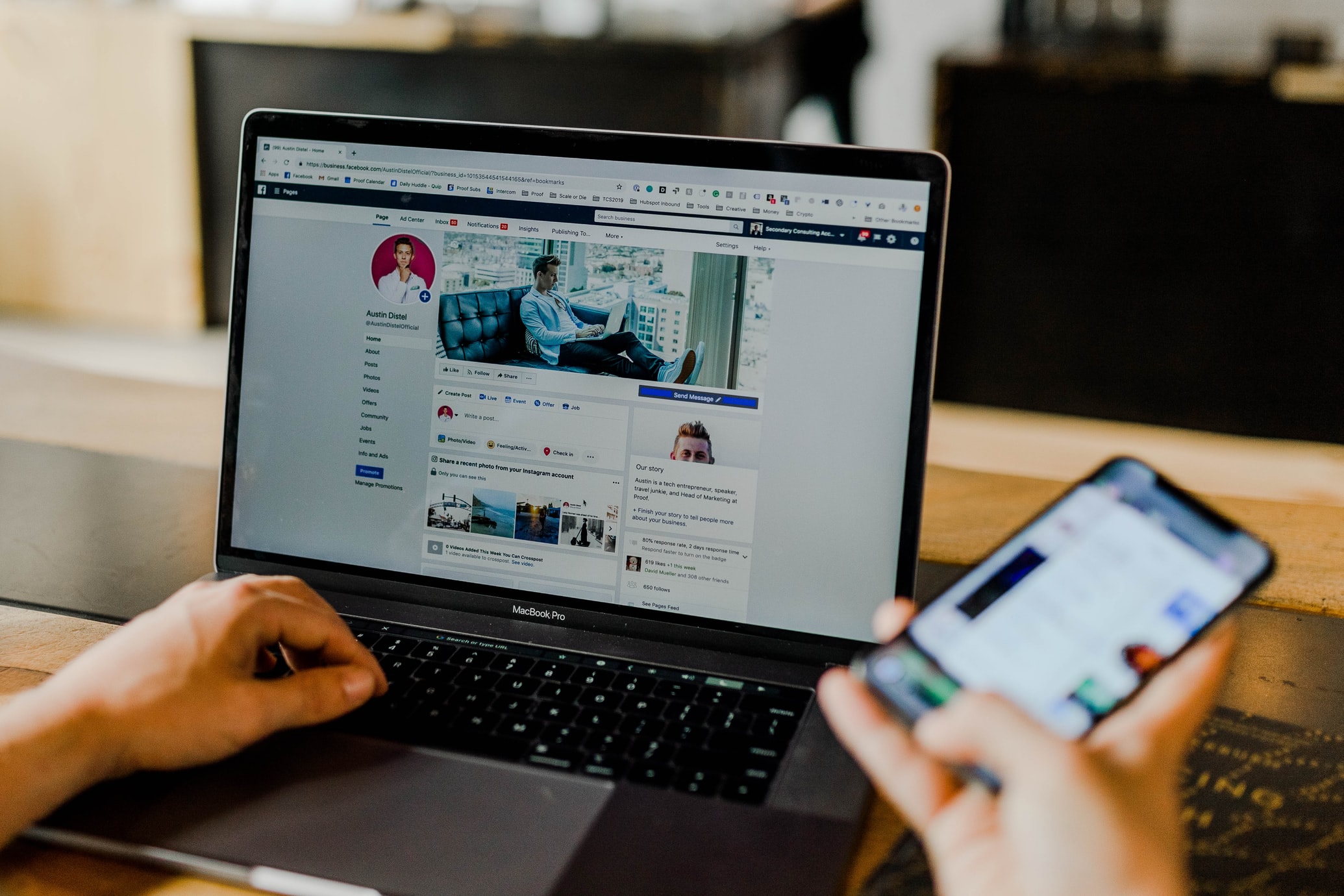 A social media manager checking a Facebook page on a Macbook and iPhone