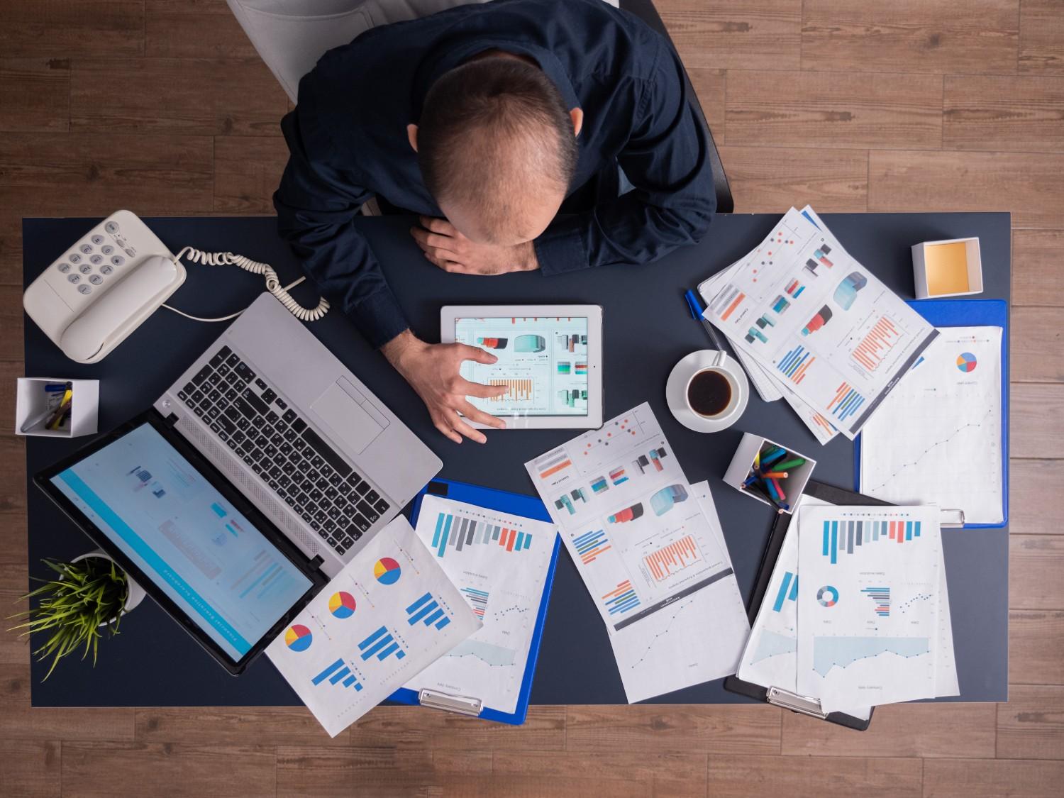 Overhead businessman analyzing data tablet desk