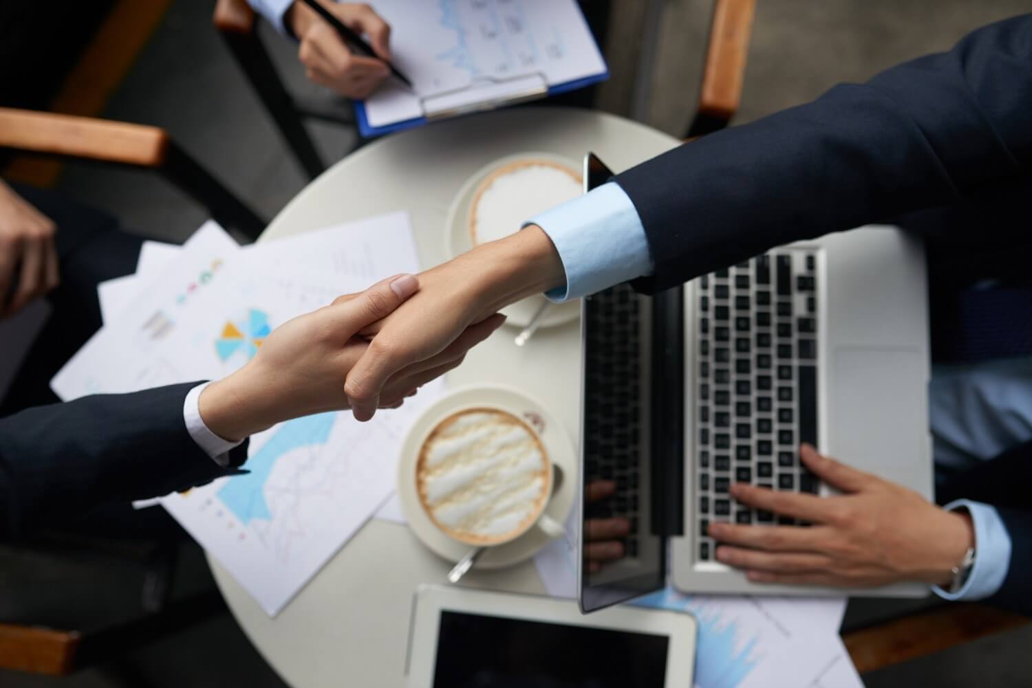 Business partners shaking hands over a table in an overhead view