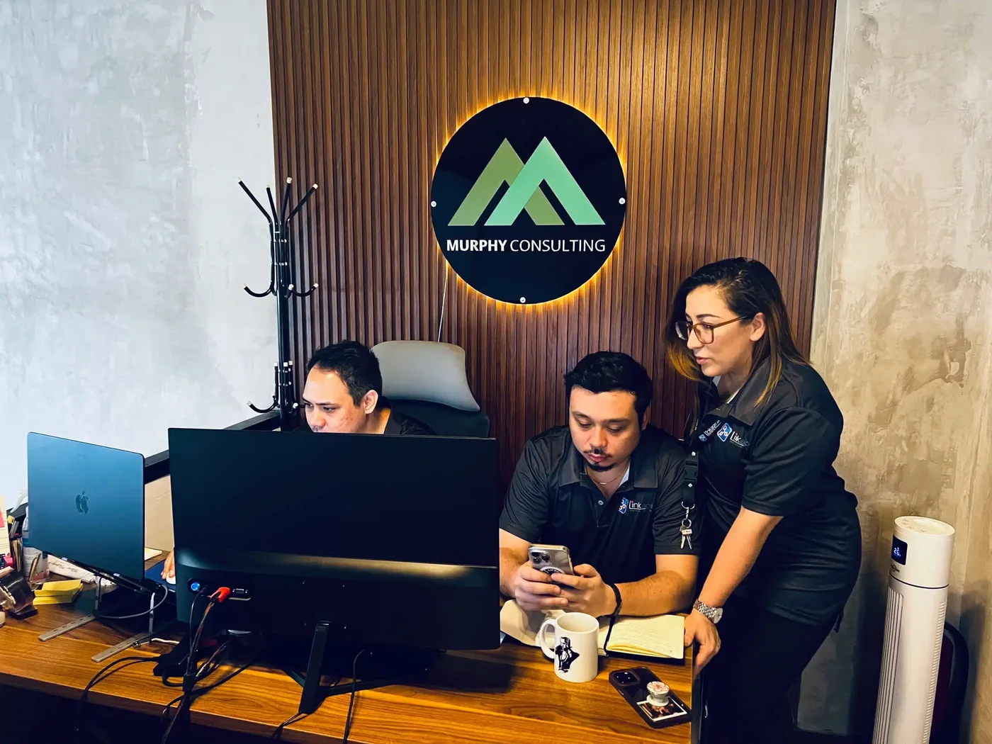 Murphy Consulting branded workstation with team members reviewing production work